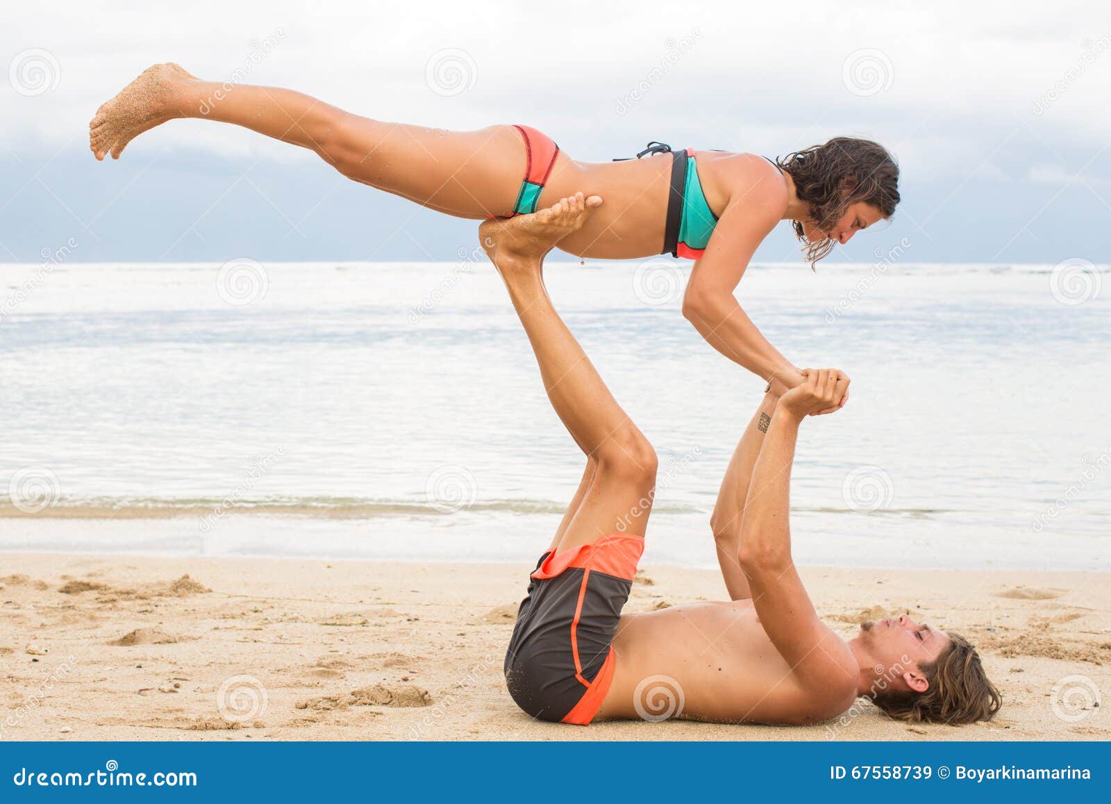 Young couple practice an exercise in trust on a tropical beach.