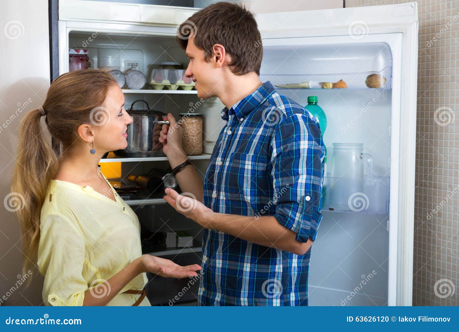 young couple standing near fridge
