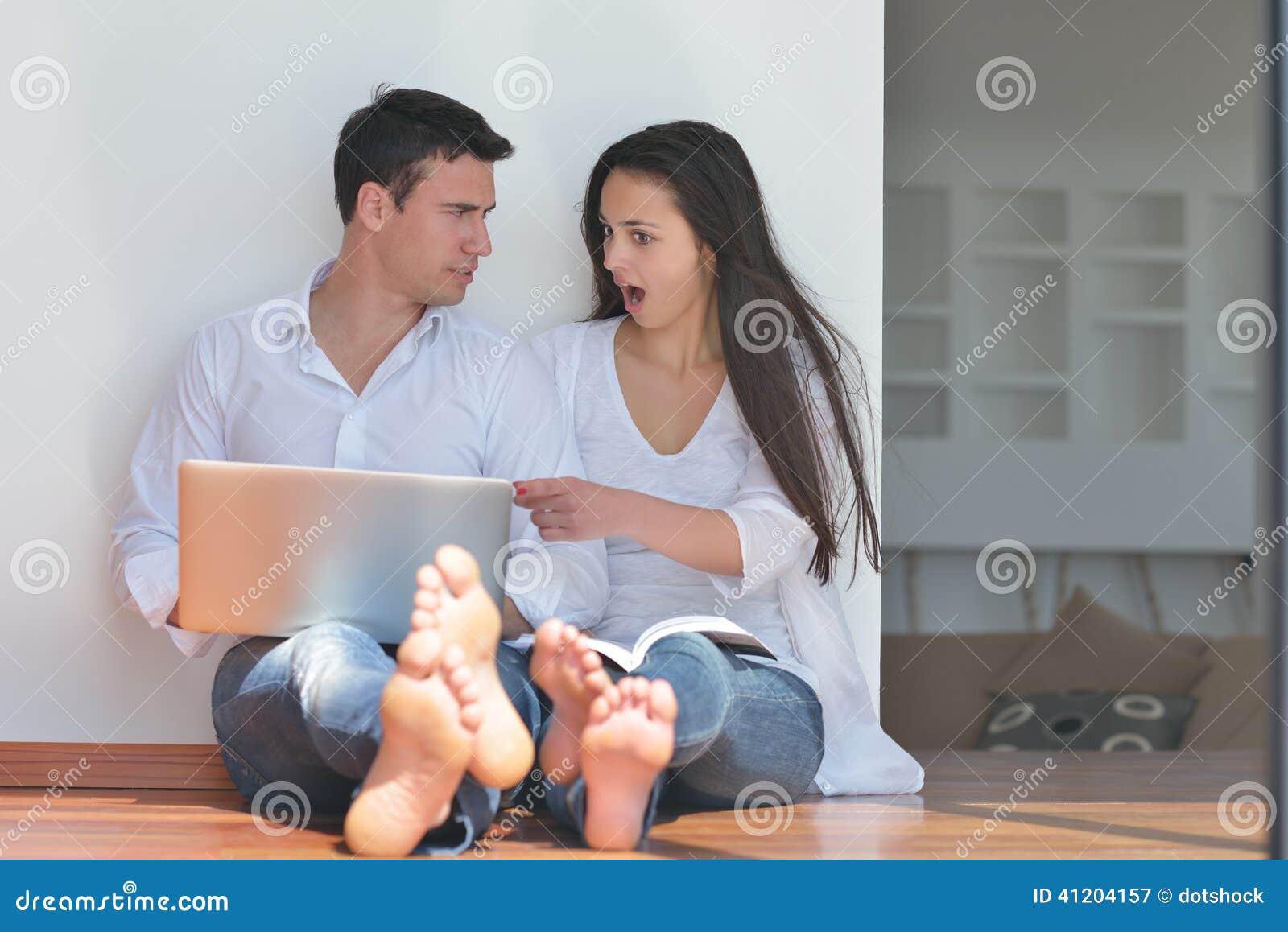 Young couple using laptop at home. Happy young relaxed couple working and playing on laptop computer at home