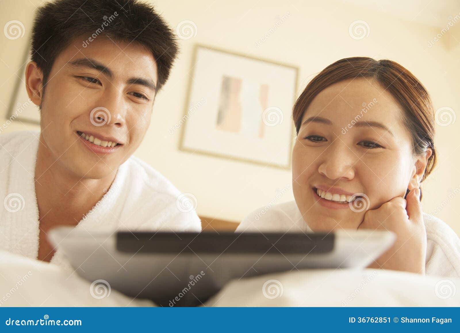 Young Couple Using Tablet in Bed. Young Couple Using Tablet in Bed