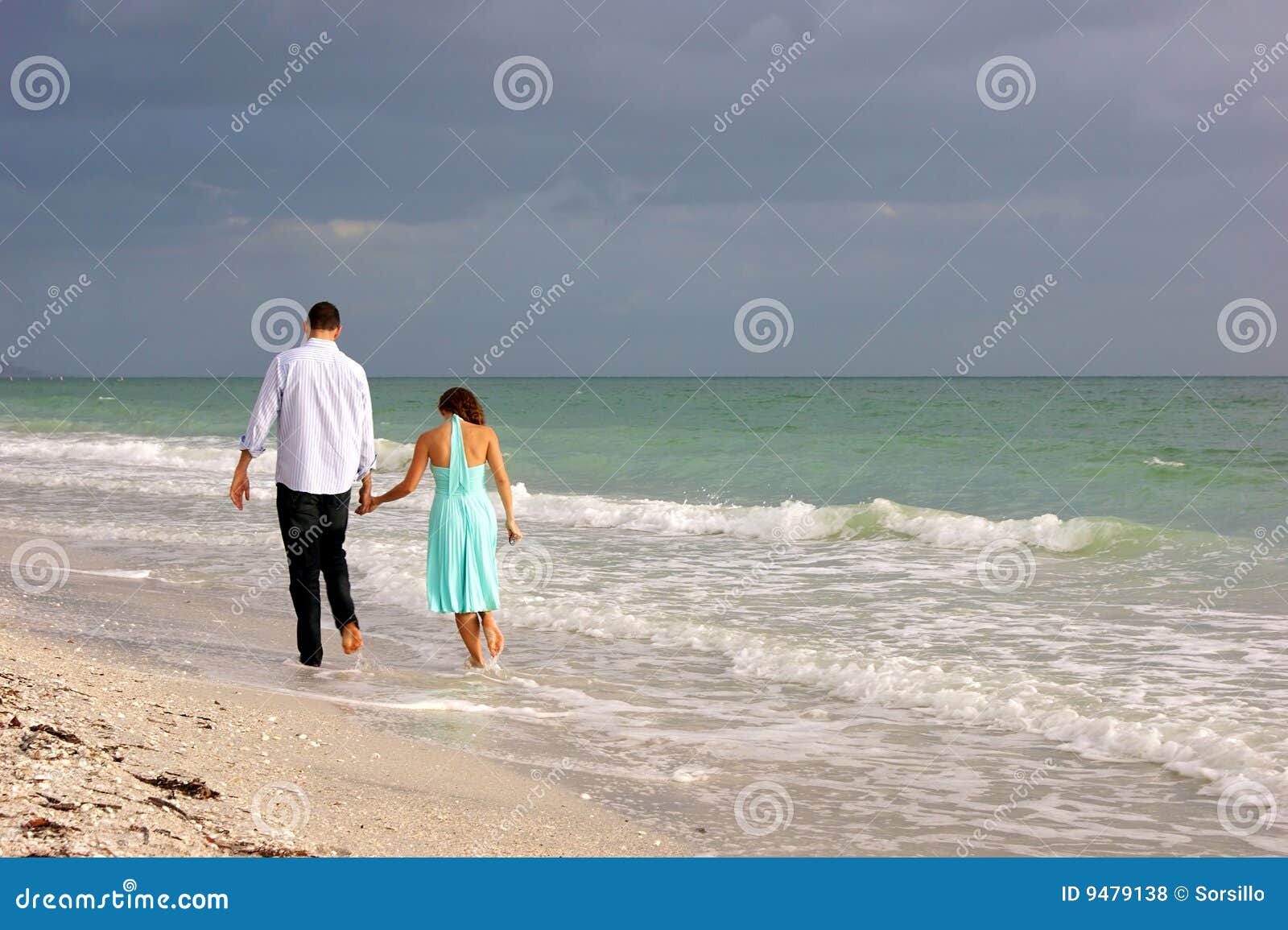 young couple walking along bonita beach as sunsets