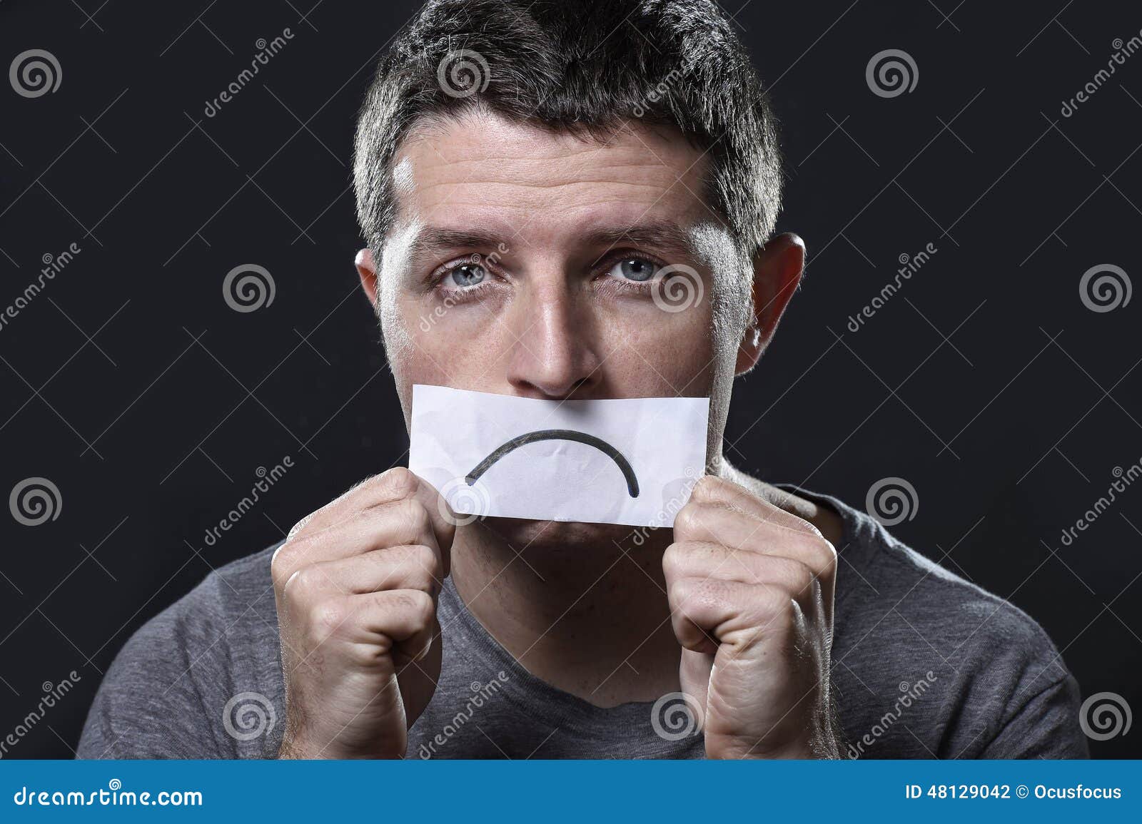 young depressed man lost in sadness and sorrow holding paper with sad mouth in depression concept