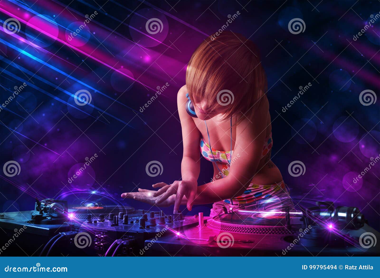 Young DJ Playing on Turntables with Color Light Effects Stock Photo