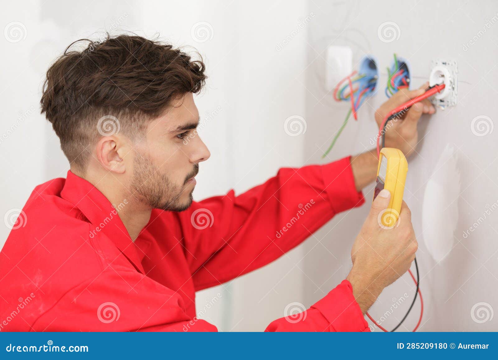 Young Electrician Checking Voltage in Electrical Wall Socket Stock