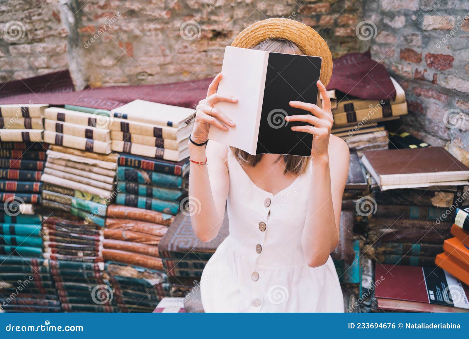 young elegant woman choosing book in ancient secondhand bookstore libreria acqua alta in venice, italy