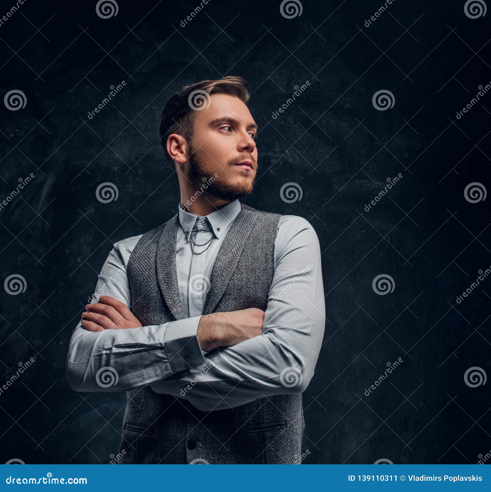 A Young Elegantly Dressed Man Posing with His Arms Crossed in a Studio ...