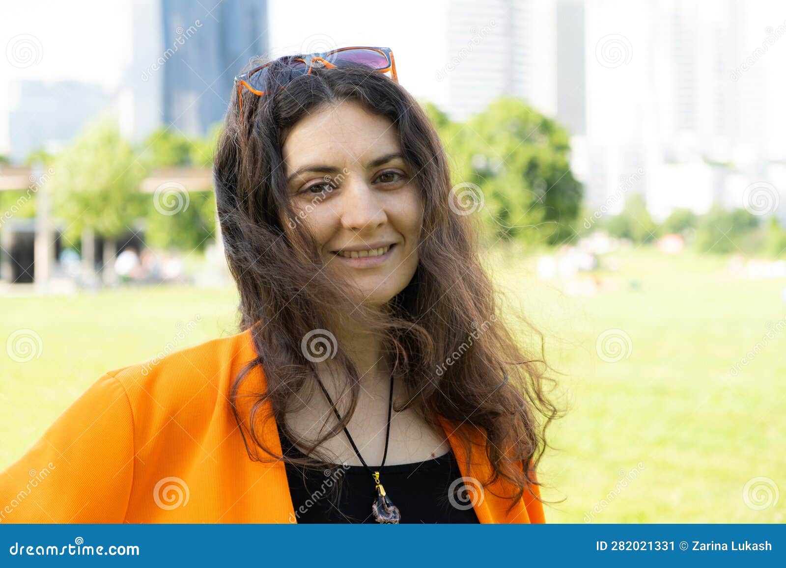 Young European Brunette Woman in Orange Suit Standing in the Park and ...