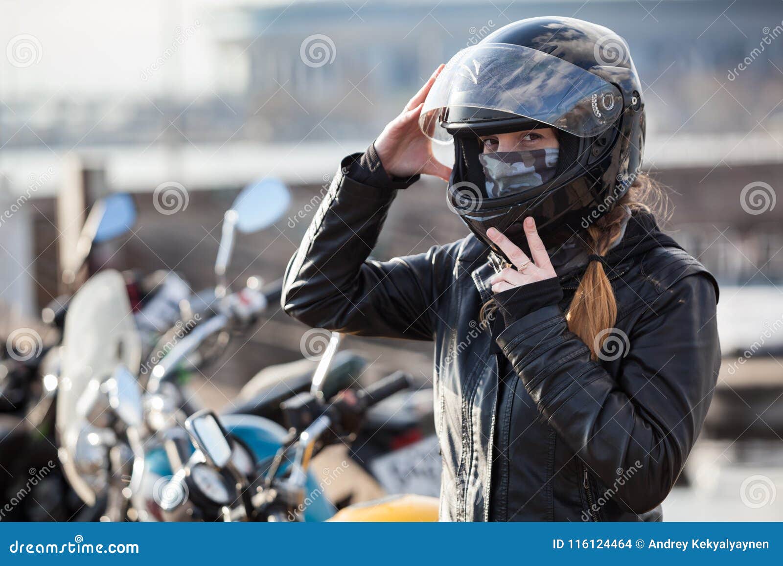 young girl biker trying black motorcycle helmet for ride on bike