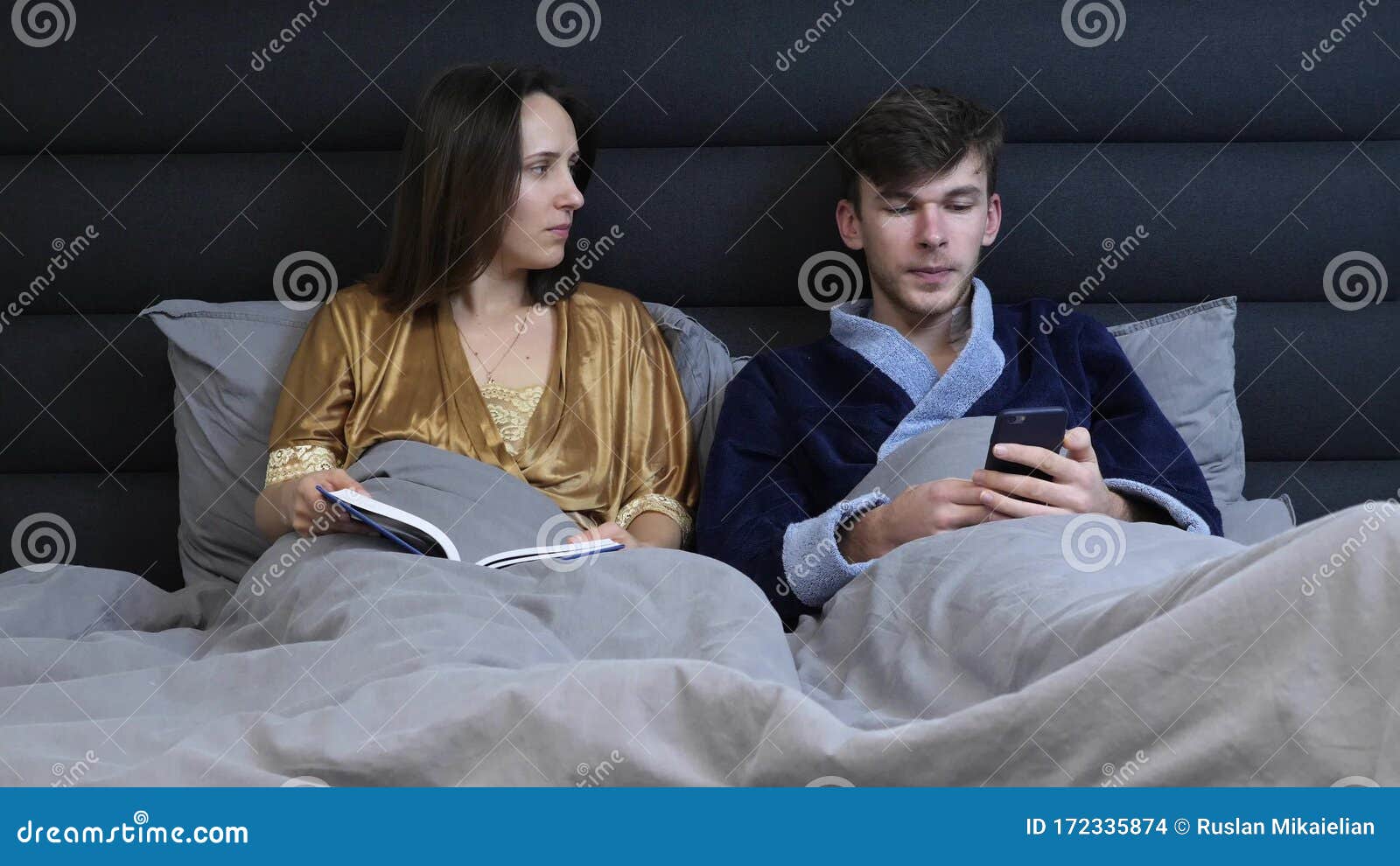 Young Family on Bed in Hotel Room Talking To Each Other