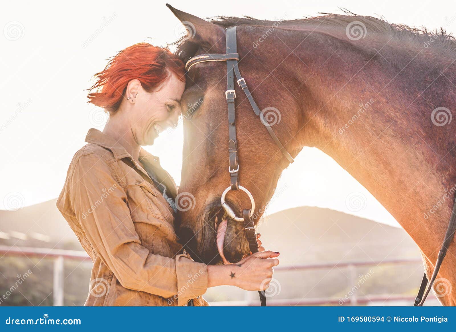 young farmer woman hugging her horse - cowgirl having fun inside equestrian corral ranch - concept about love between people and