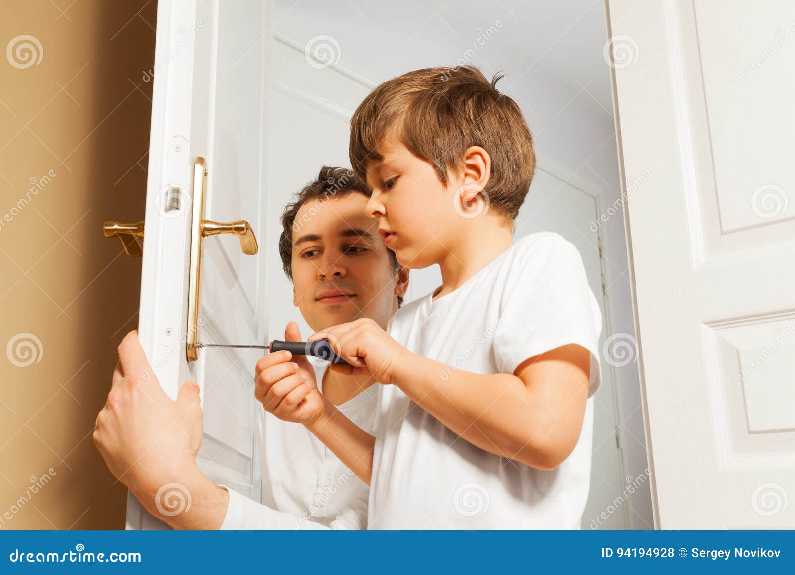 young father helping his son to fix door-handle