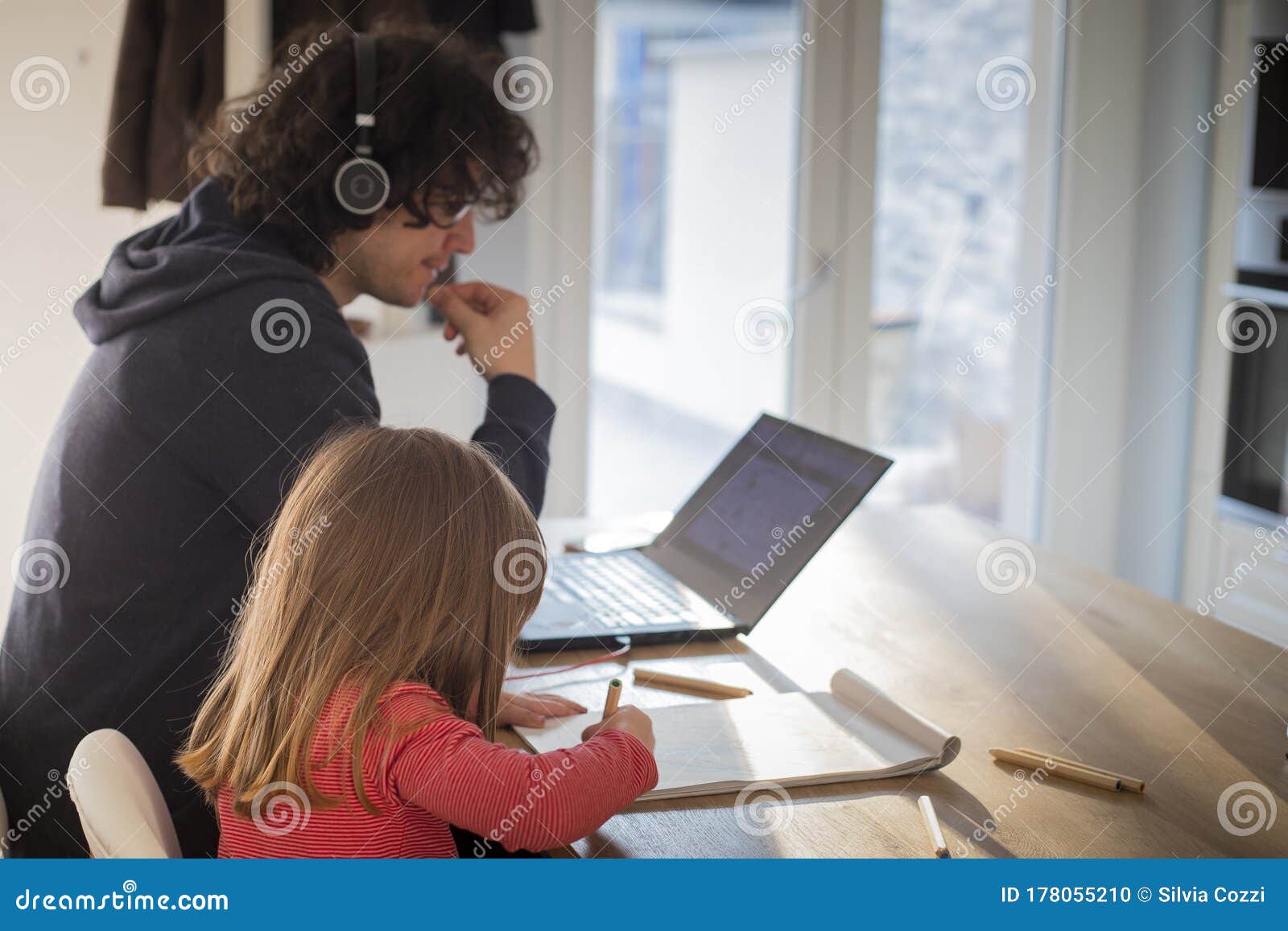 father working from home with little daughter during covid-19 lockdown. side view, profile