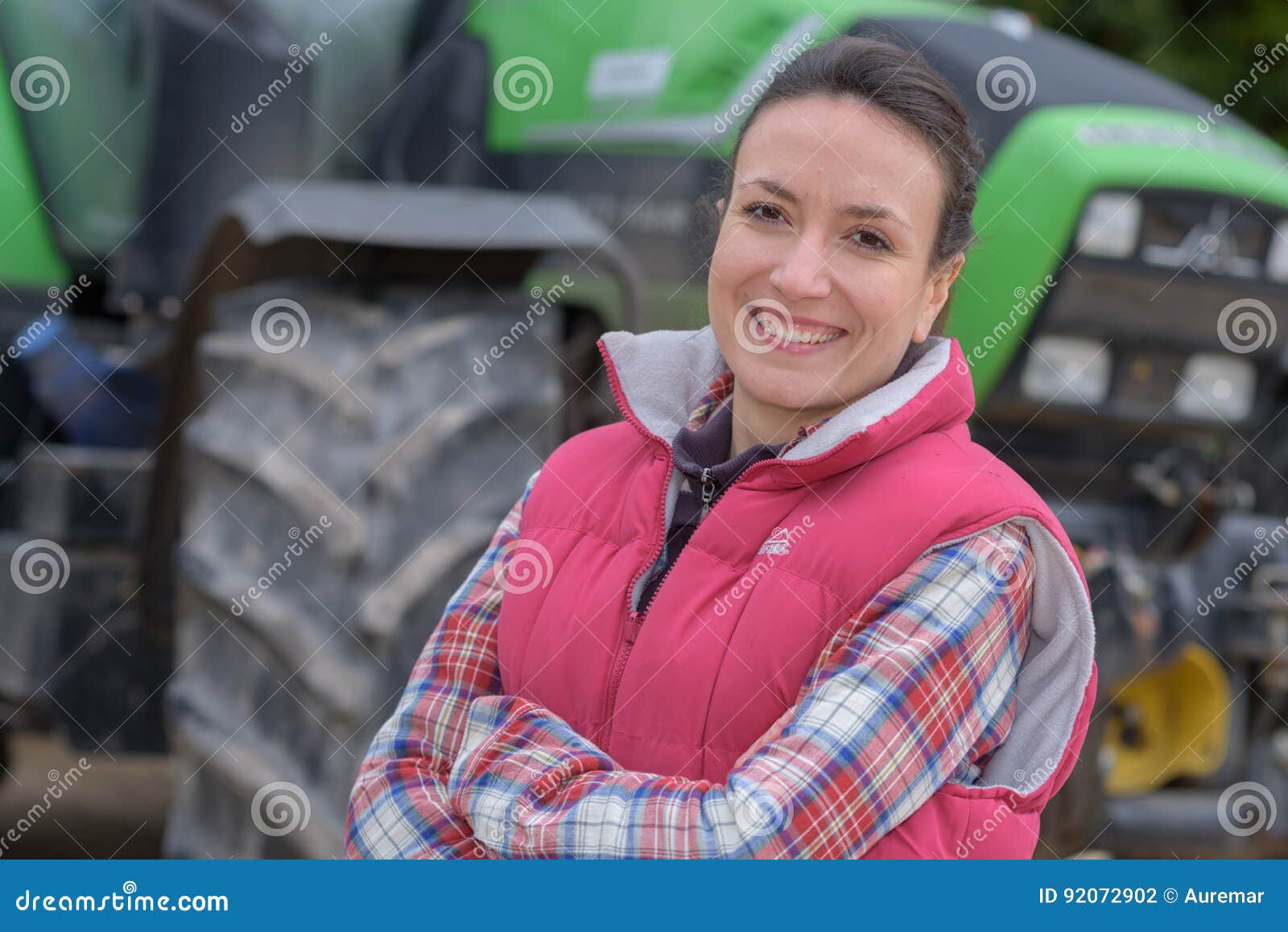 young female agricultor on field tractor in background
