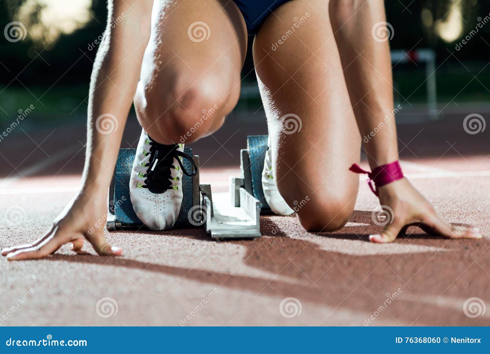 young female athlete launching off the start line in a race.