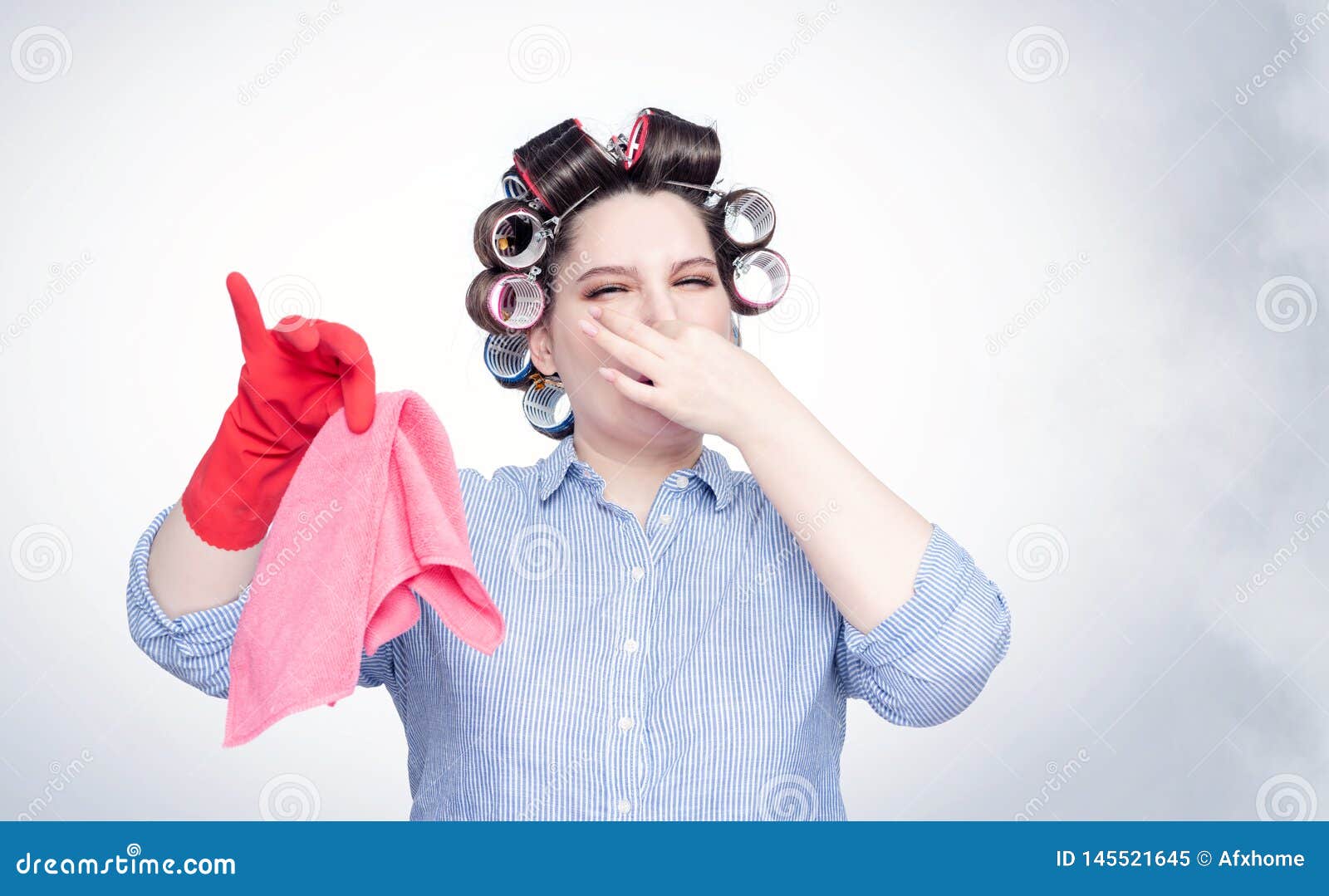 young female in hair curlers emotionally pinches her nose with a hand from the stench.