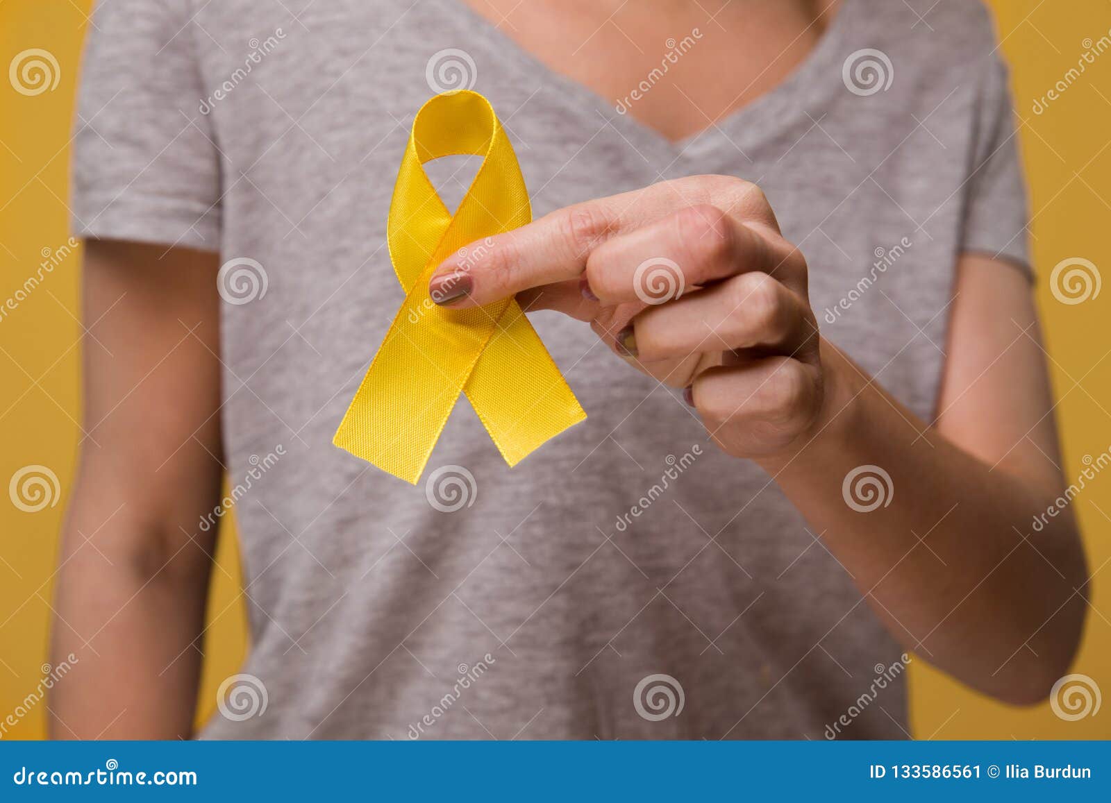 young female holding yellow gold ribbon awareness  for endometriosis, suicide prevention, sarcoma bone cancer