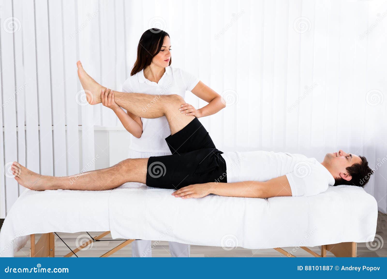 young female masseur giving leg massage to man