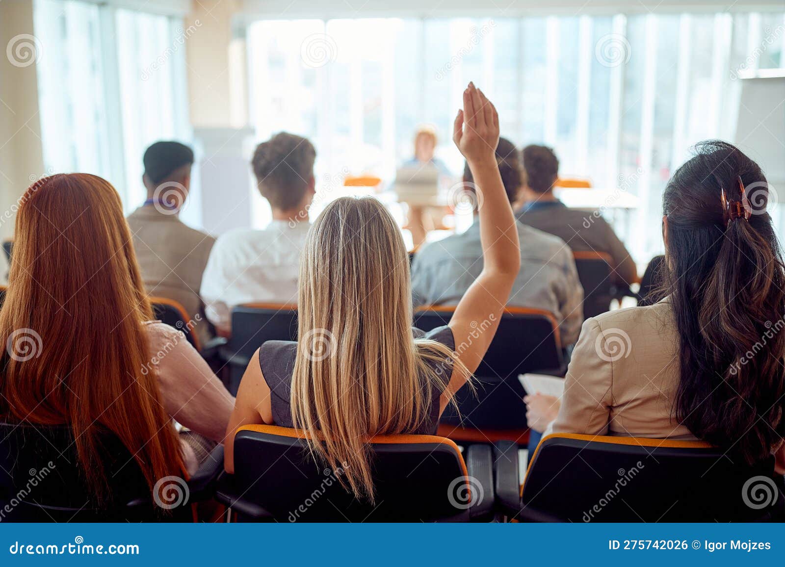 a young female participant is raising a hand to ask a question during a business lecture in the conference room. business, people