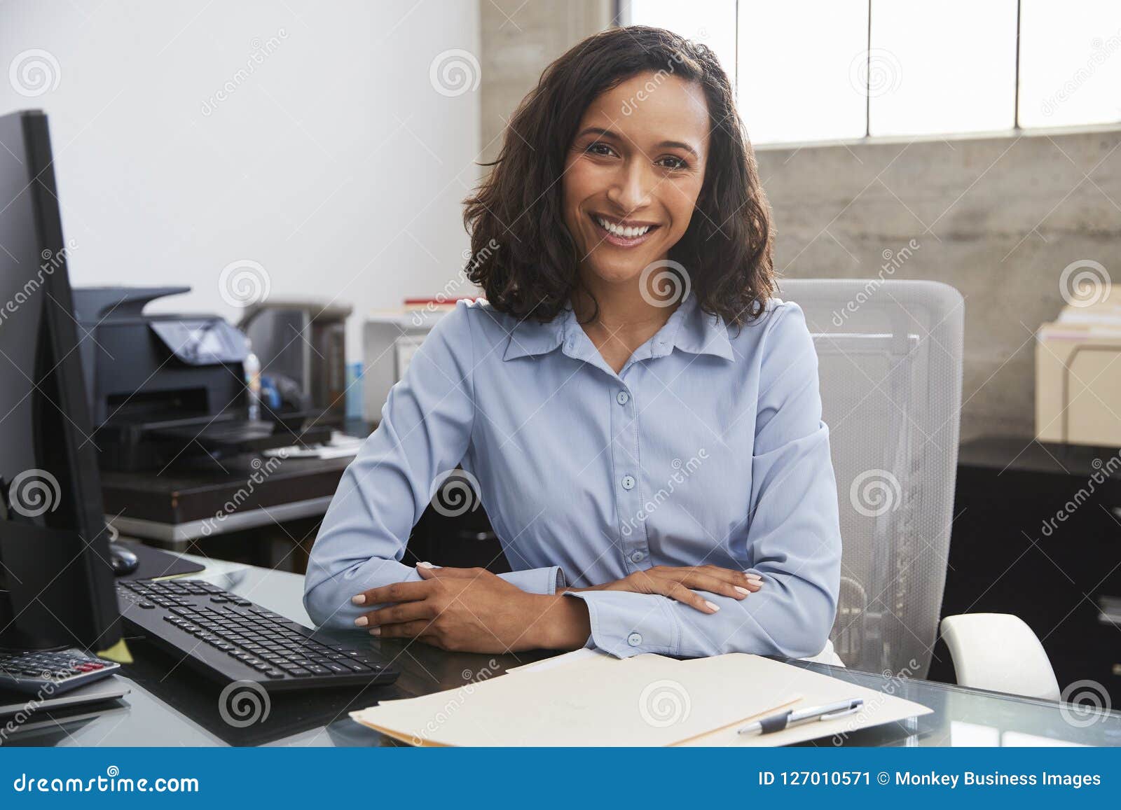 young female professional at desk smiling to camera