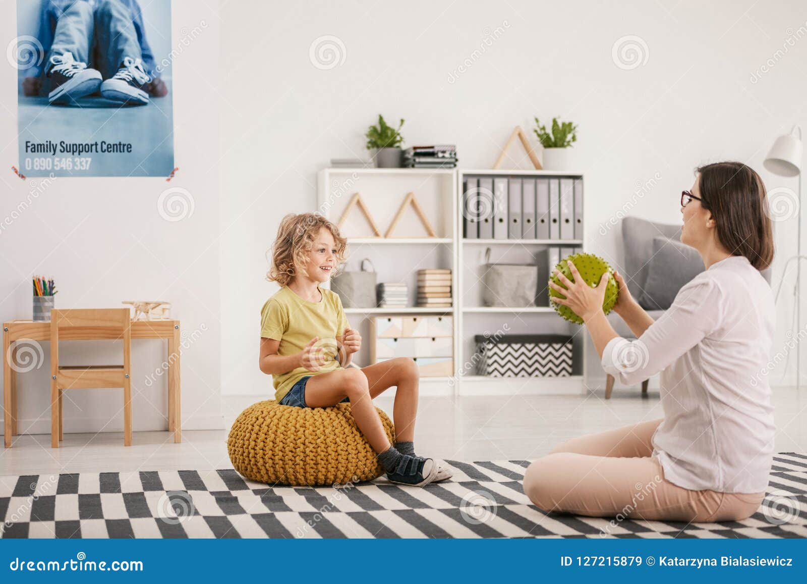 young female therapist playing with a happy orphaned boy during