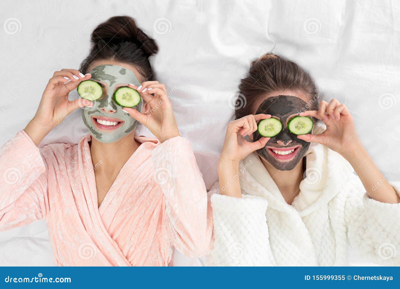 young friends with facial masks having funon bed at pamper party, top view