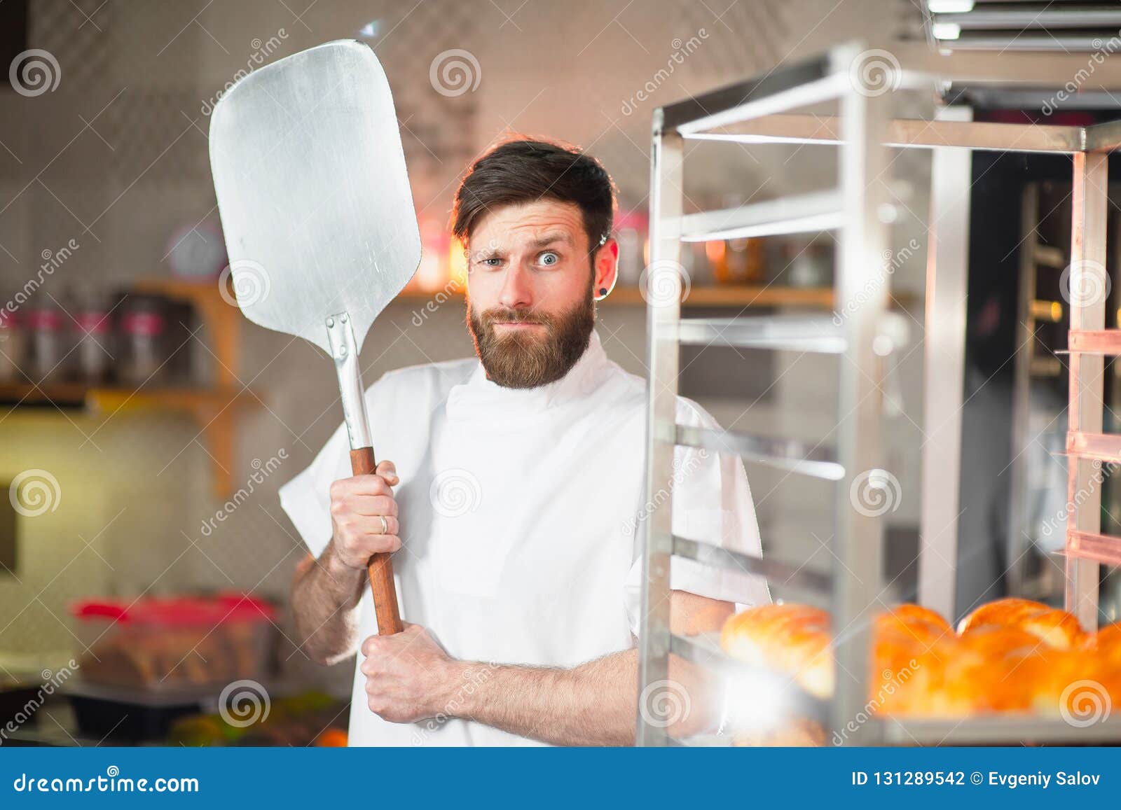 A Young Funny Baker with a Pizza Spatula in His Hands Against the