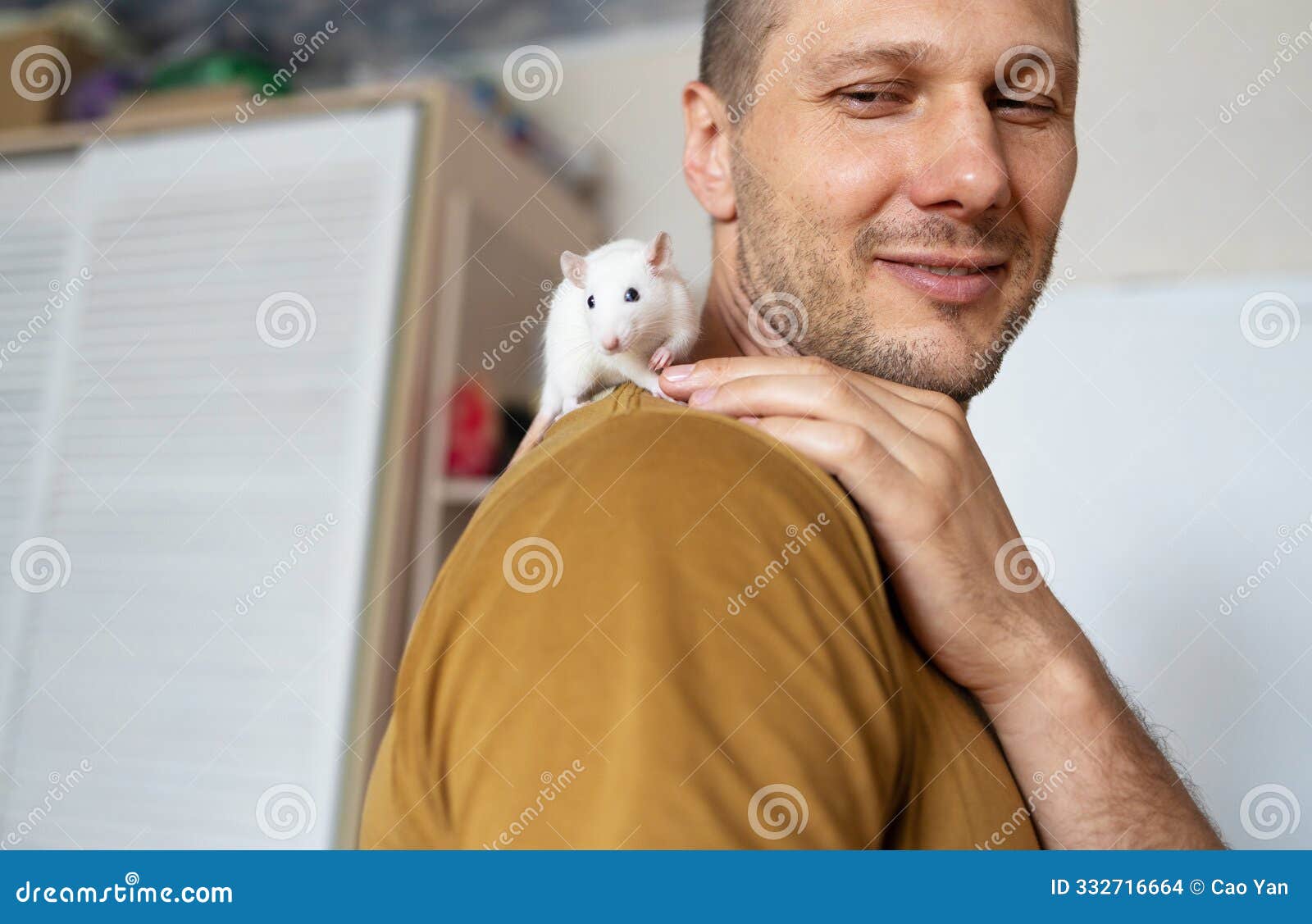 young caucasian man plays with cute rat on his shouder at home