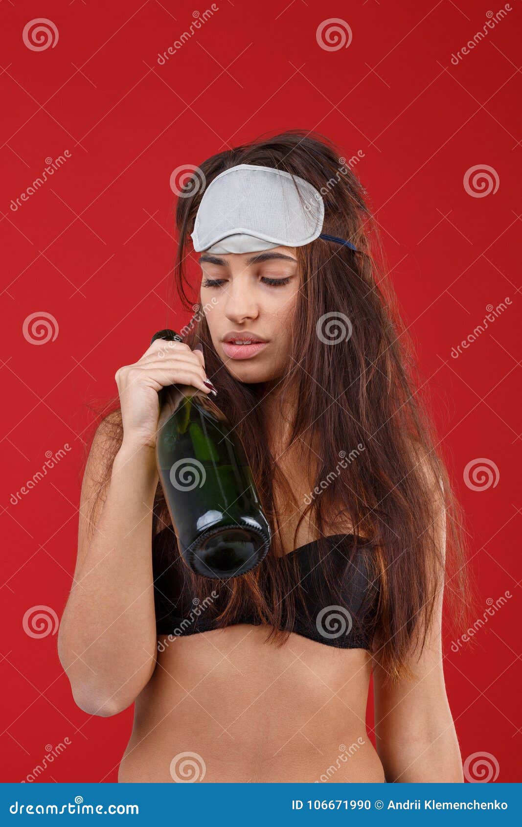 Free Shipping on All Orders A Young Girl, in a Bra and a Sleeping Mask,  Holds a Bottle of Alcohol and Looks at it. on a Red Background. Stock Photo  - Image