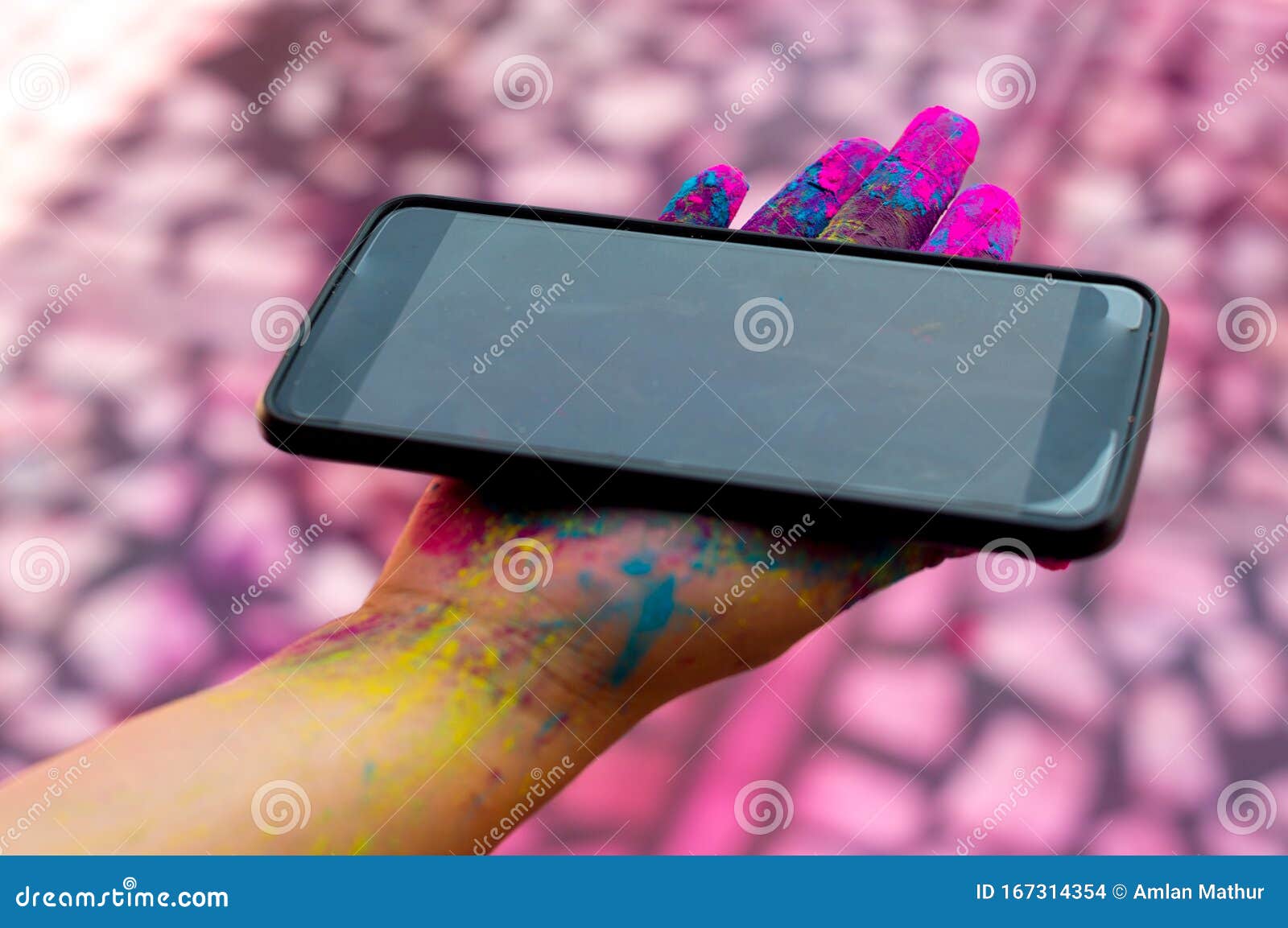 young girl with colored gulaal powder on her hands holding a mobile phone during the festival of holi