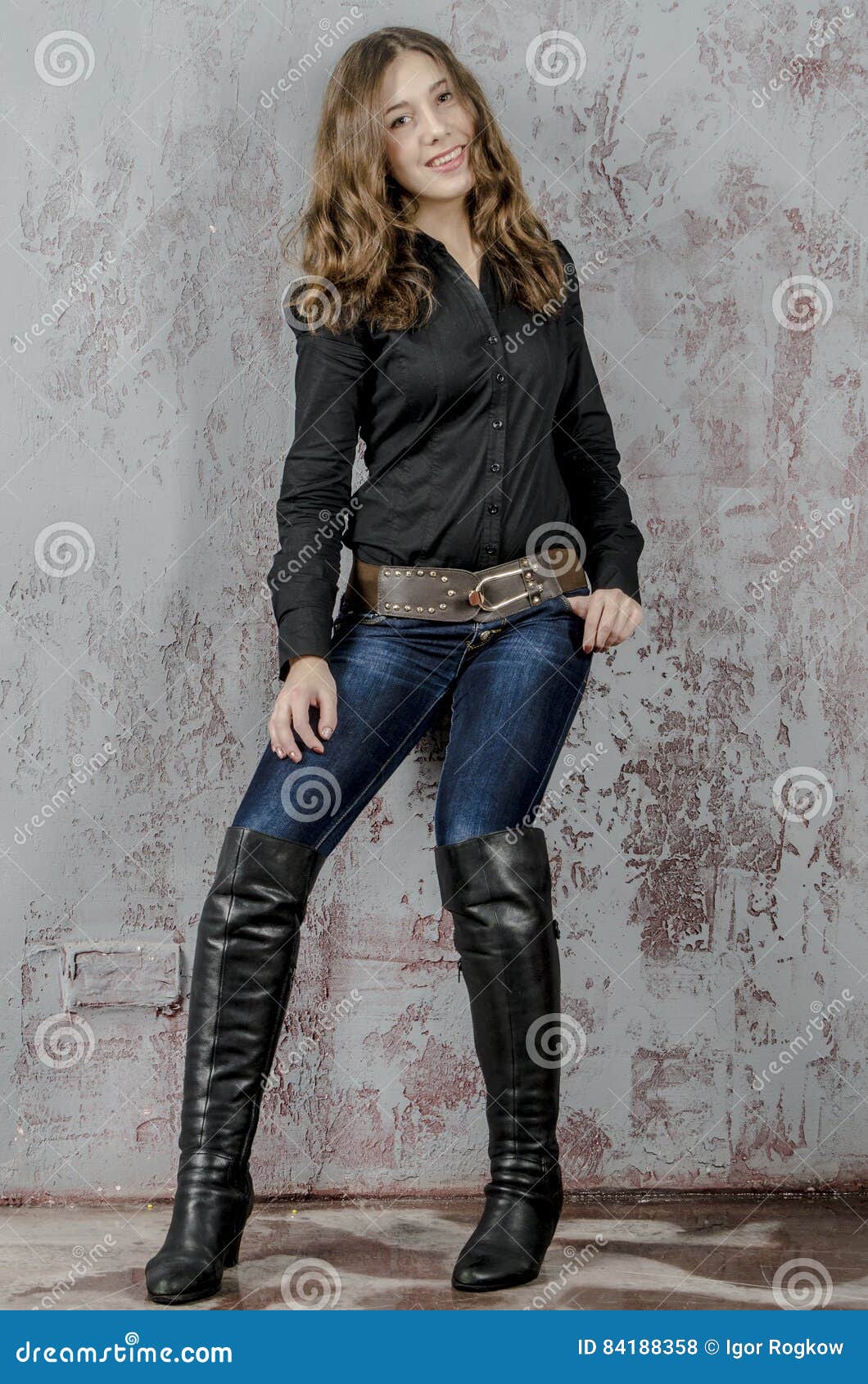 Young Girl with Curly Hair in a Black Shirt, Jeans and High Boots ...