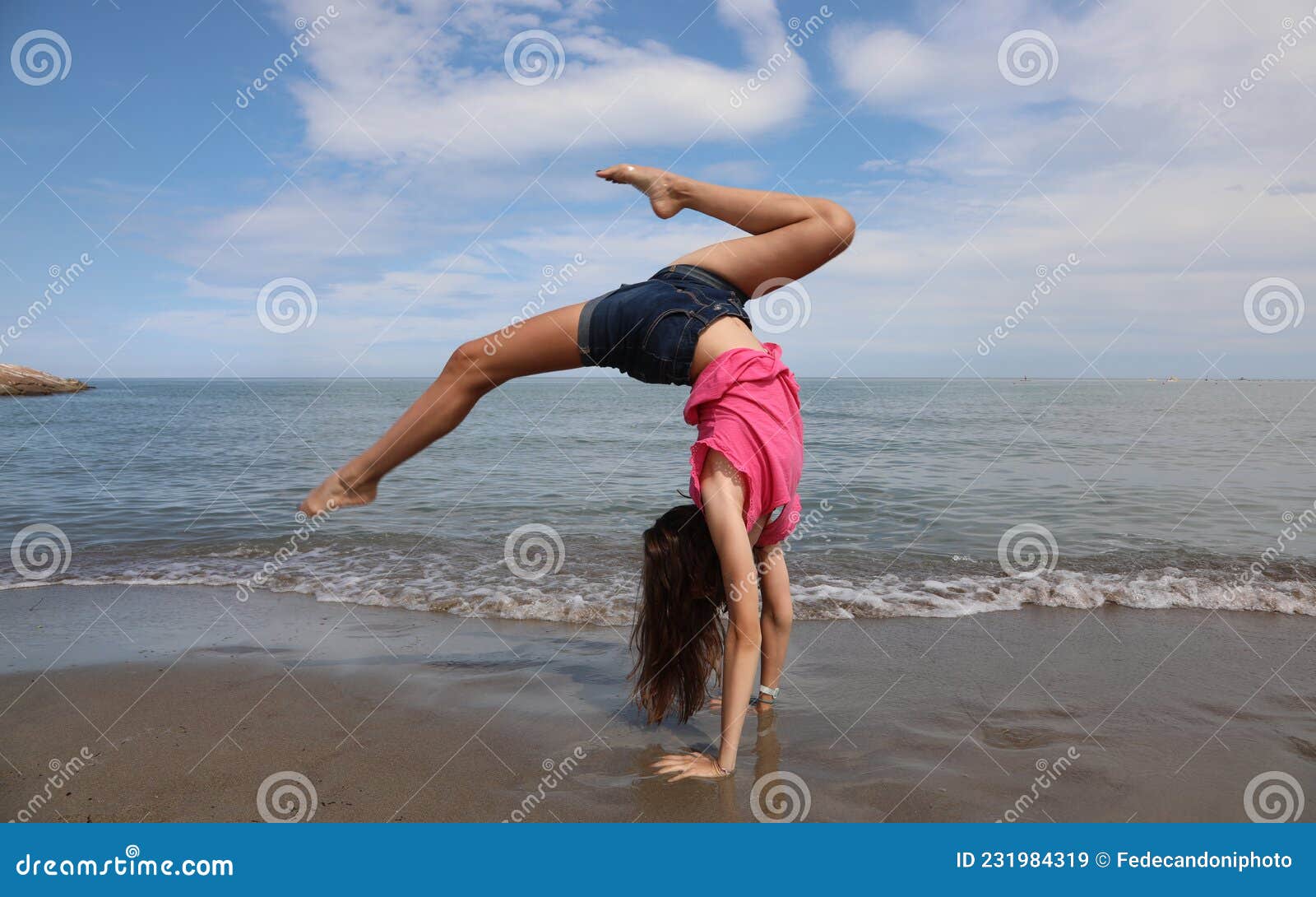 Girl Does a Spin and Reverse Wheel during Exercises by the Sea Stock