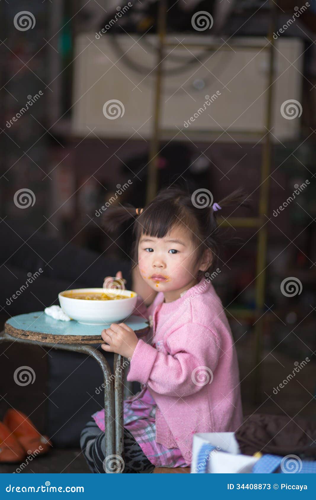 Young girl Eating on a blue table in Shanghai. SHANGHAI, CHINA, APRIL 28: Unidentified young girl eating and looking at the camera in Shanghai, 2013.