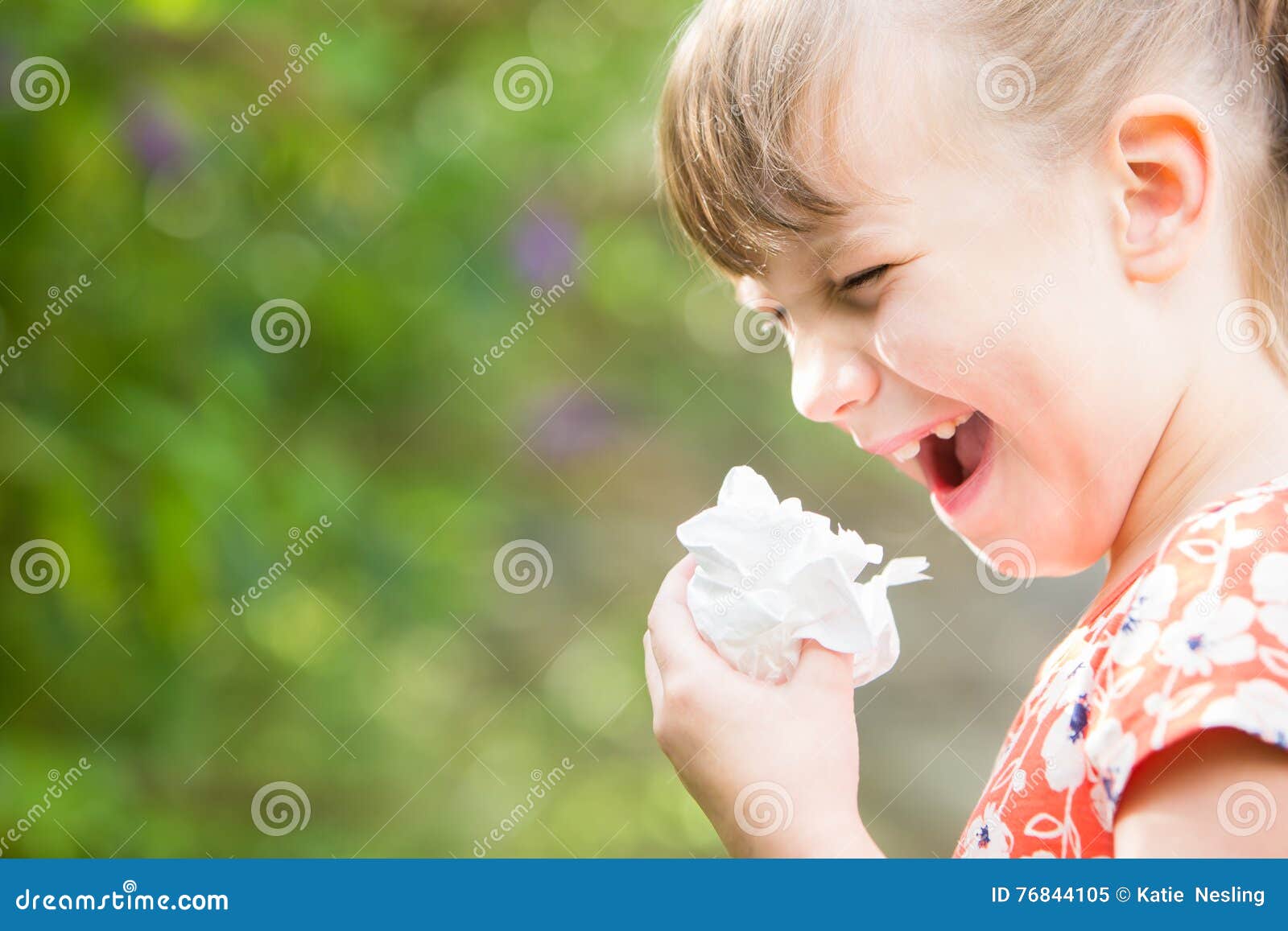 young girl with hayfever sneezing in garden