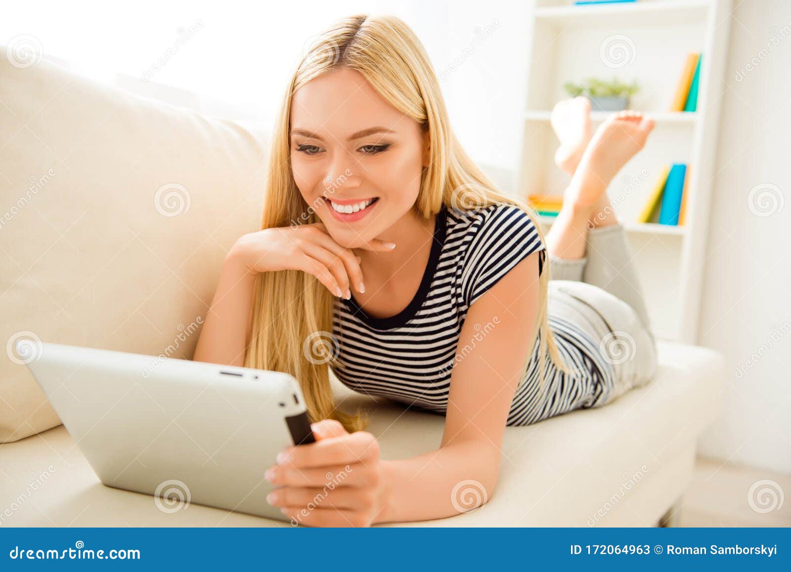 Young Girl Lying on Sofa and Reading Book on Tablet Stock Image - Image ...