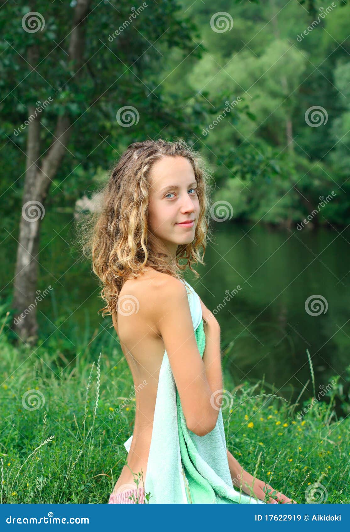 Intriguing nude model photo portfolio - Stunning woman sitting on grass near the lake.