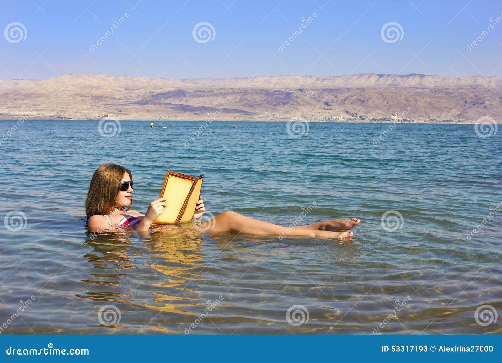 young girl reads a book floating in the dead sea in israel