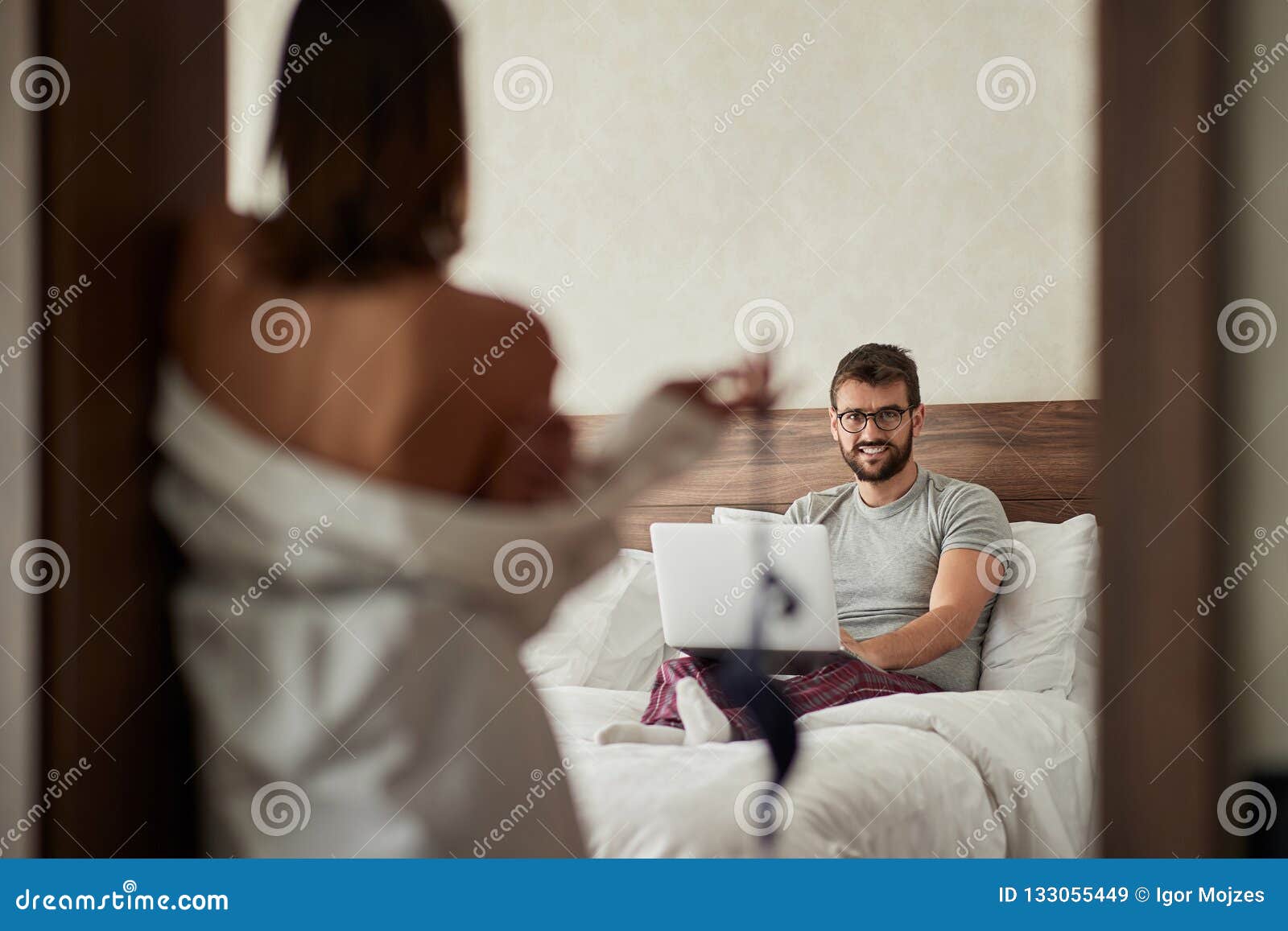 Girl Seduces a Man Who Works on a Laptop for Sex in the Bedroom Stock Image  photo