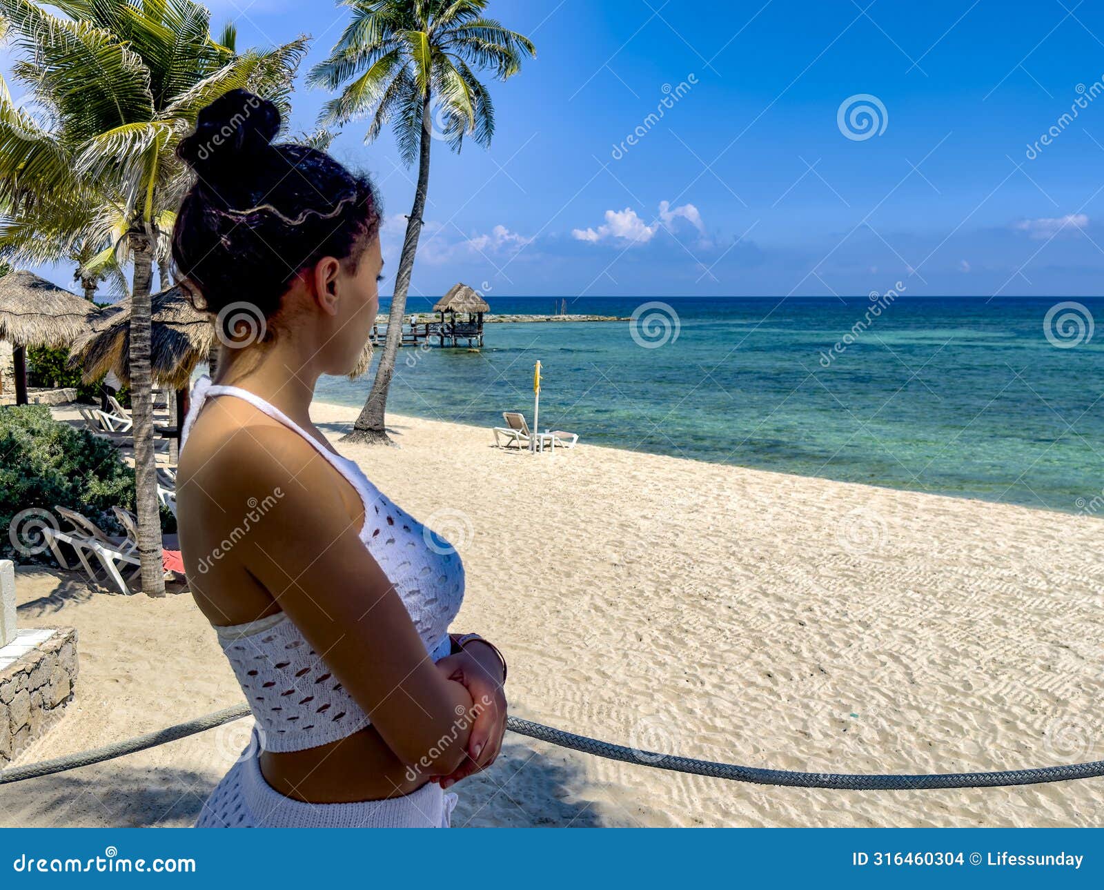 young girl in sexy clothes contemplating the horizon of a paradisiacal beach