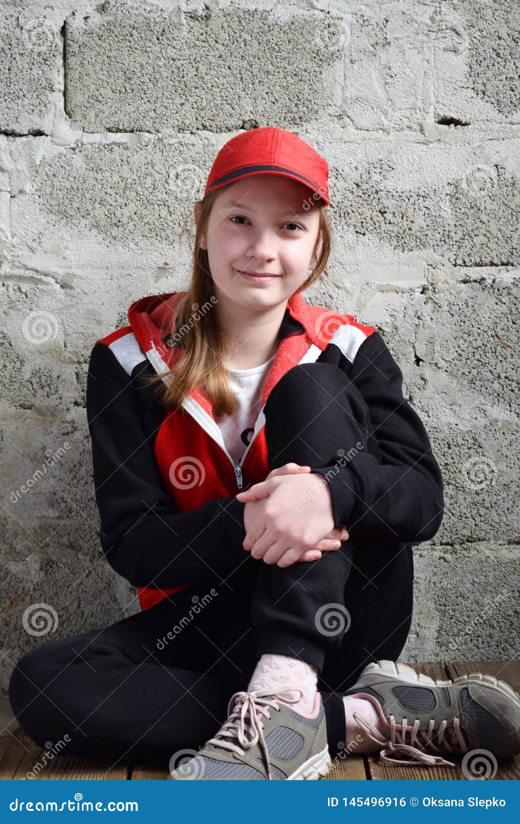 Young Girl is Sitting in Black Sports Suit, Red Cap and Smiling ...