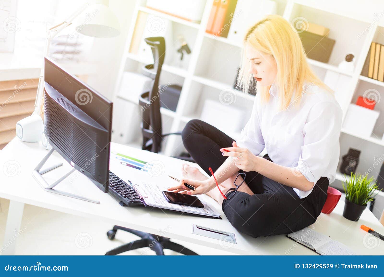 A Young Girl Sitting On A Desk In The Office And Working With