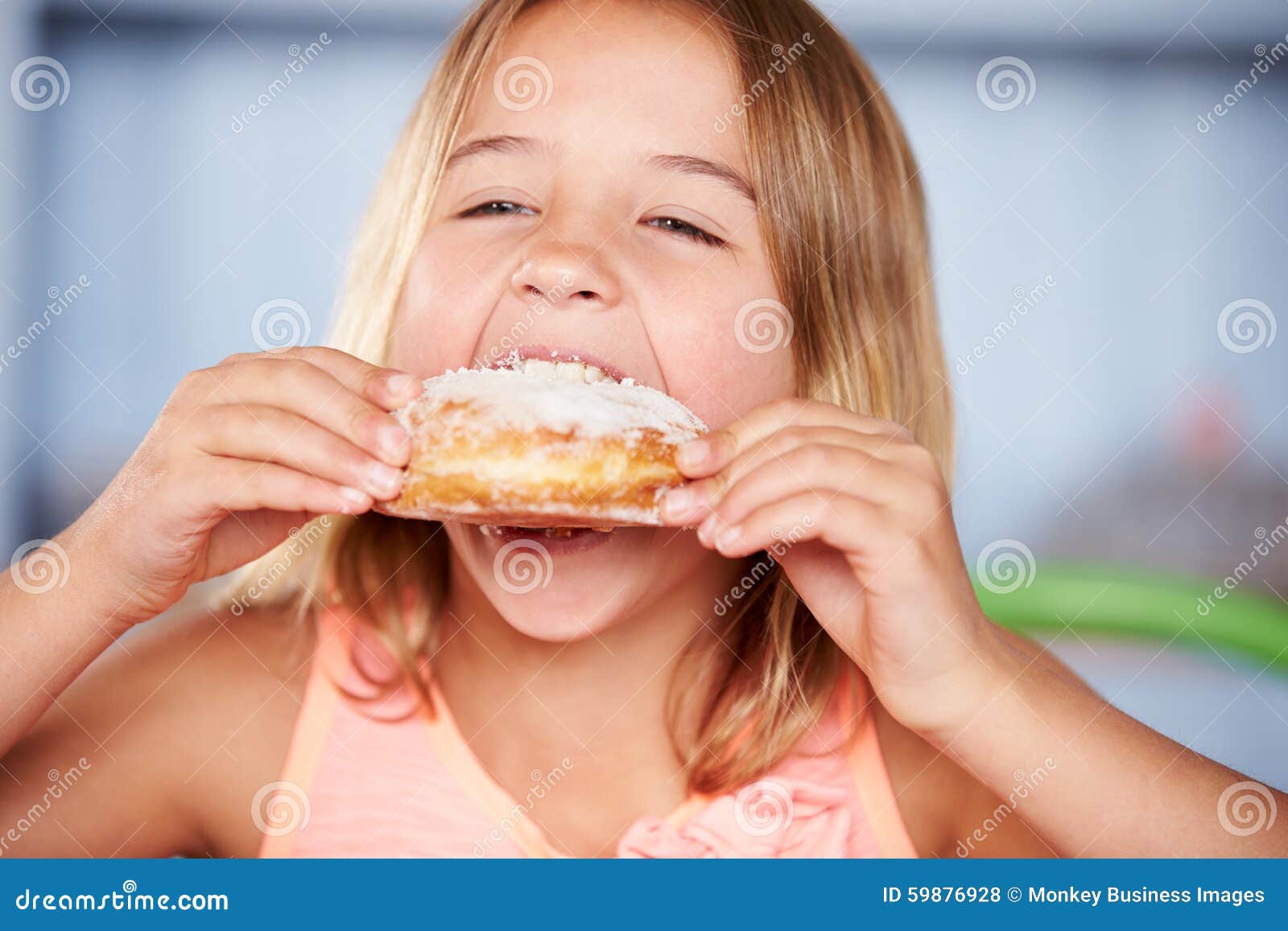 young girl sitting at table eating sugary donut