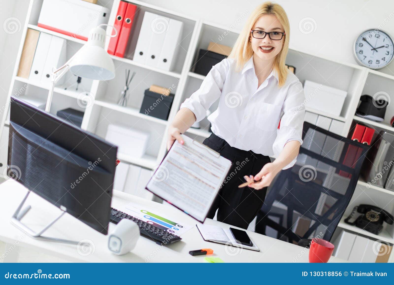 A Young Girl Stands In The Office At A Computer Desk And Stretches