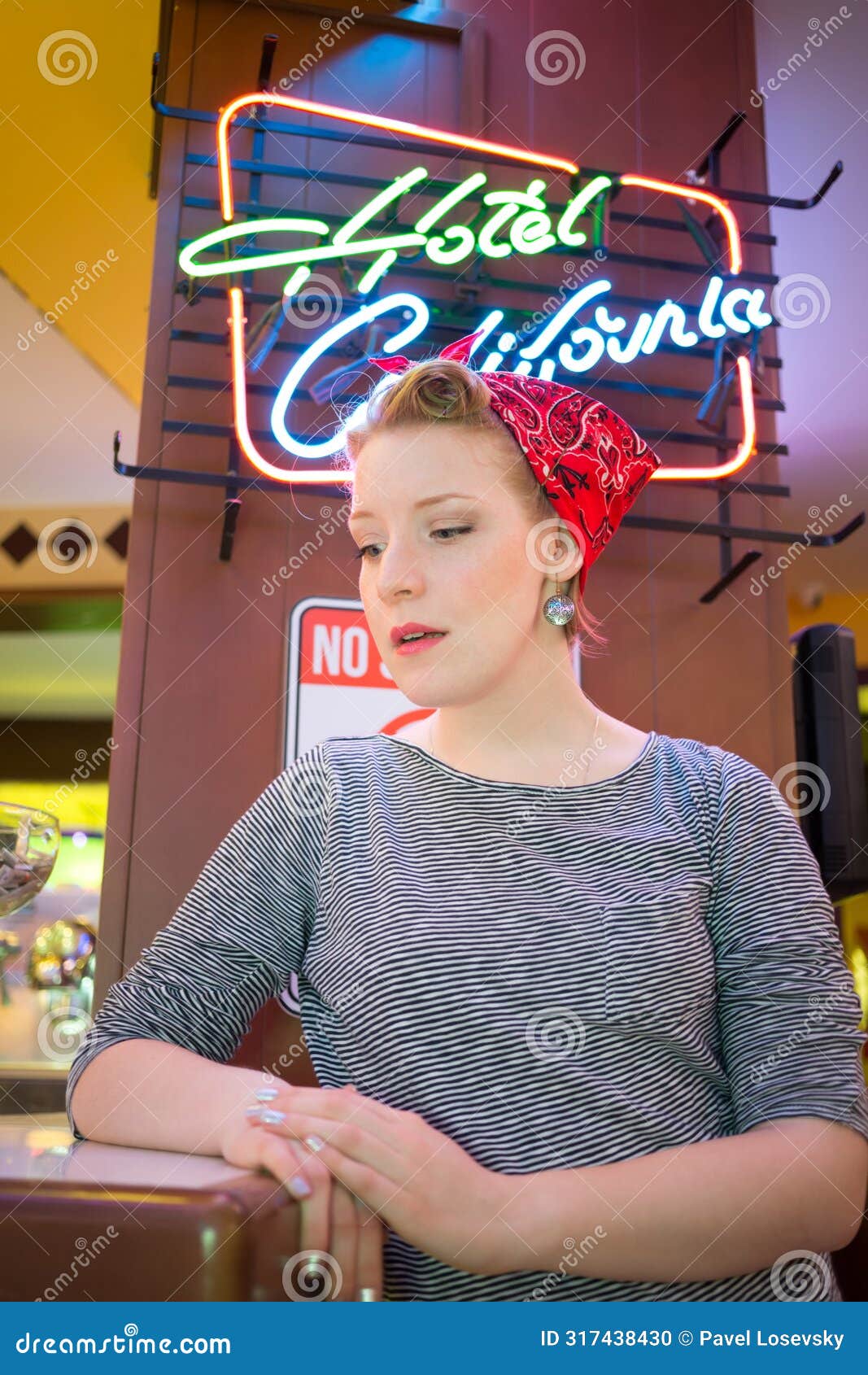 young girl in striped vest near neon signboard in