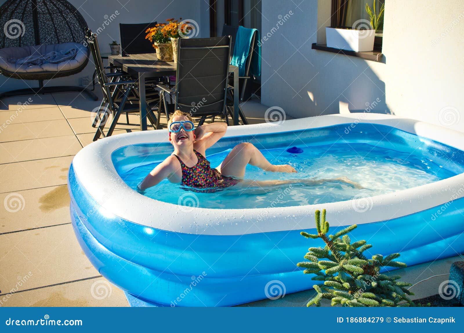 young girl swimming in inflatable swimming pool on home backyard terrace. staycation sta home concept