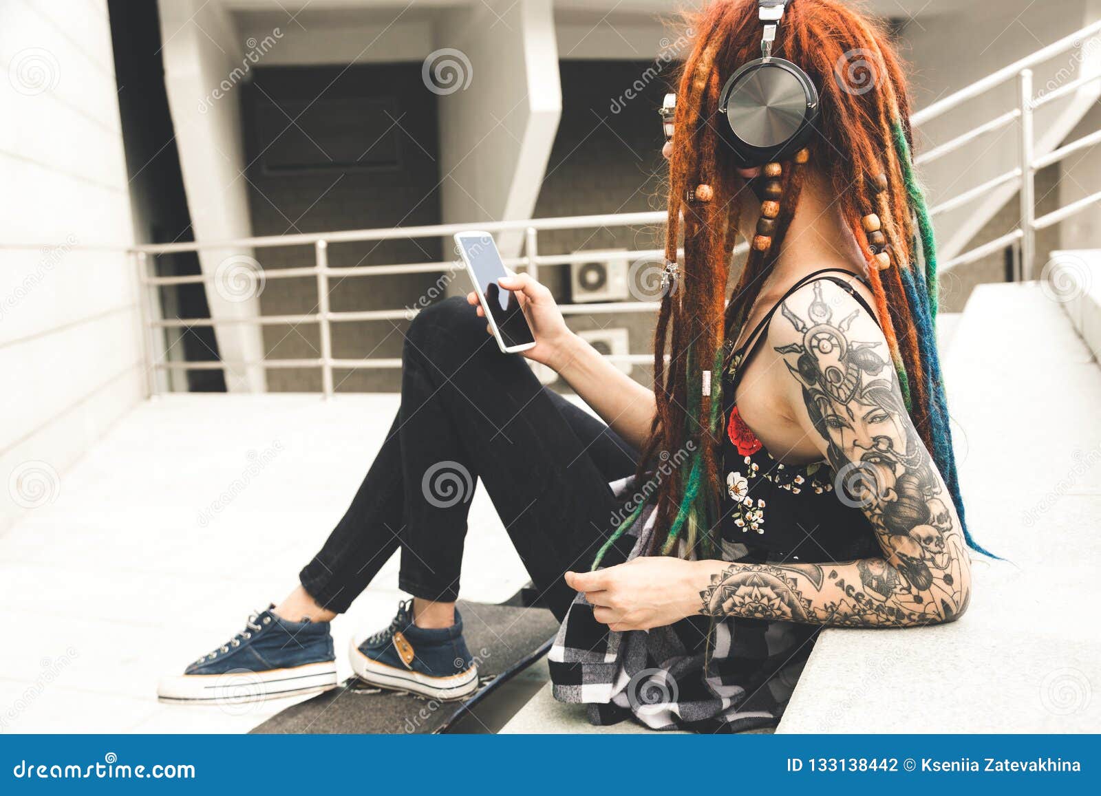 Young Girl With Tattoo And Dreadlocks Listening To Music