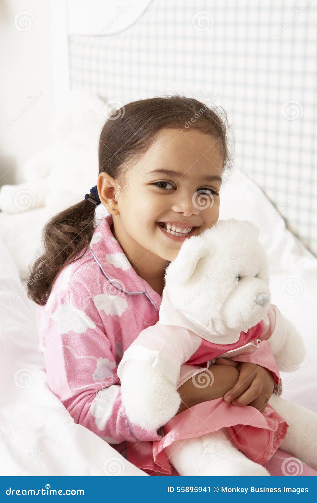 young girl wearing pajamas in bed with cuddly toy