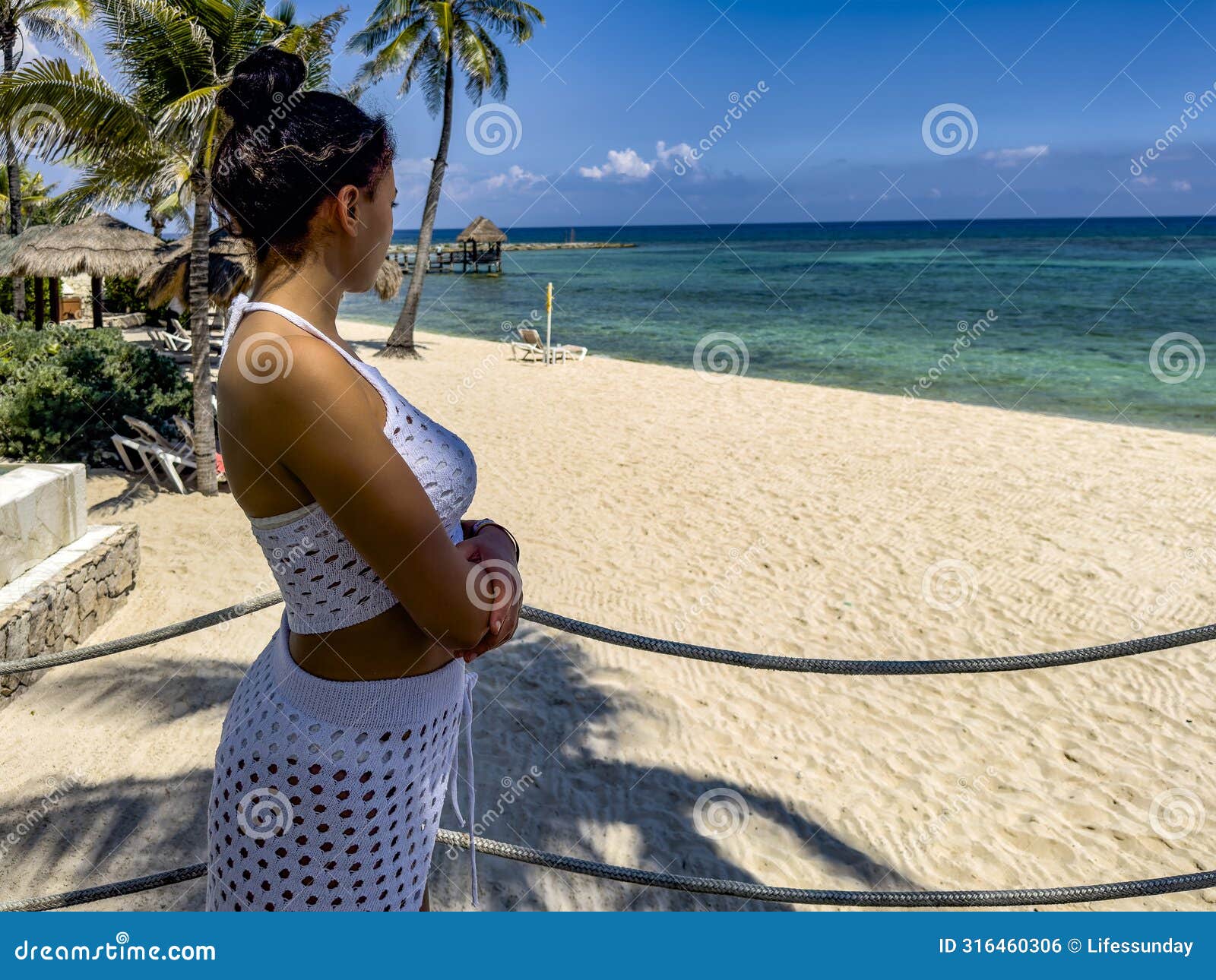 young girl in white sexy clothes contemplating the horizon of a paradisiacal beach