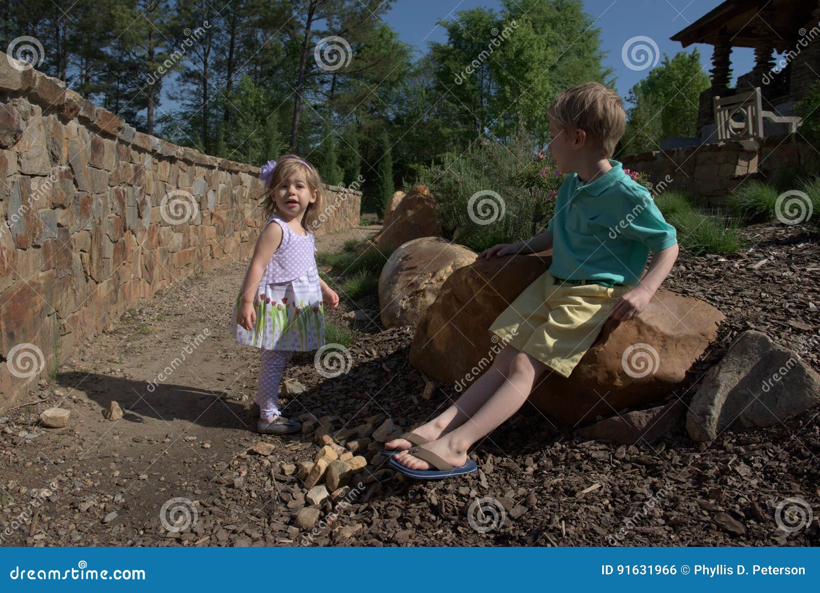 A Young Girl Of 3 Years And A Boy Of 5 Years Rest In A Rock Garden