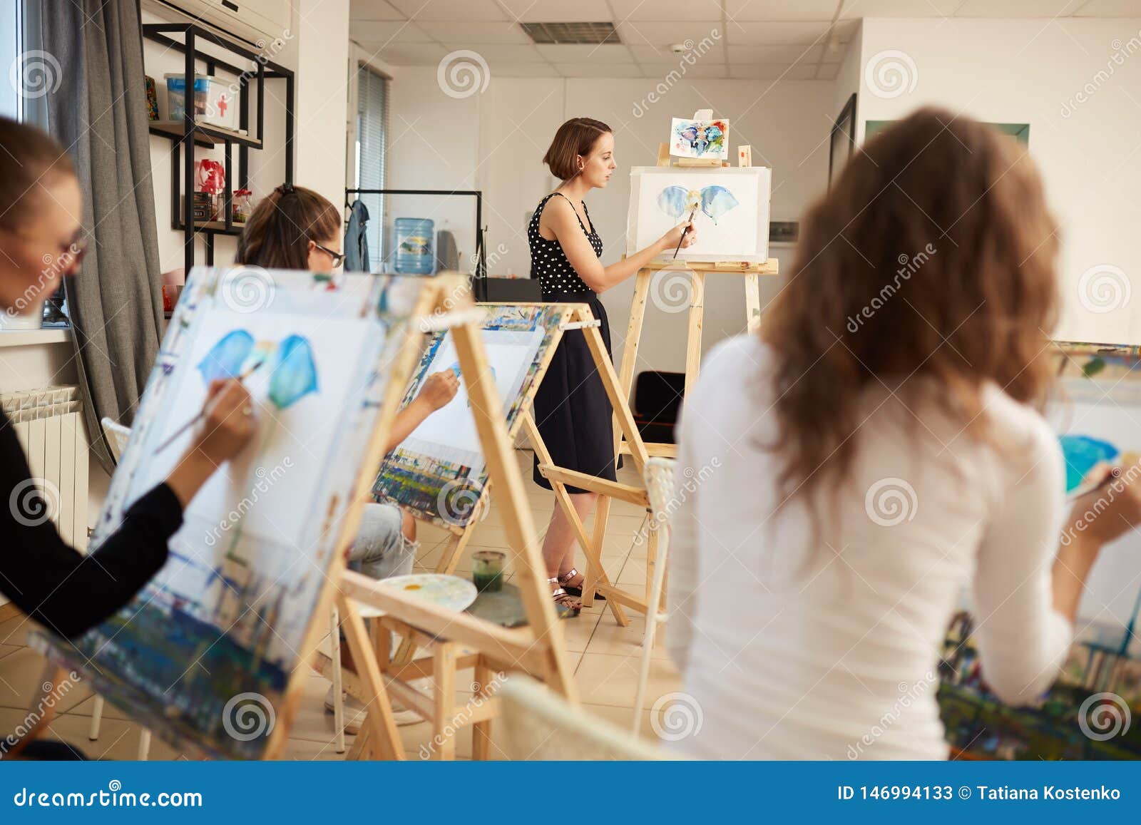 Young Girls And Drawing Teacher Paint Pictures Sitting At