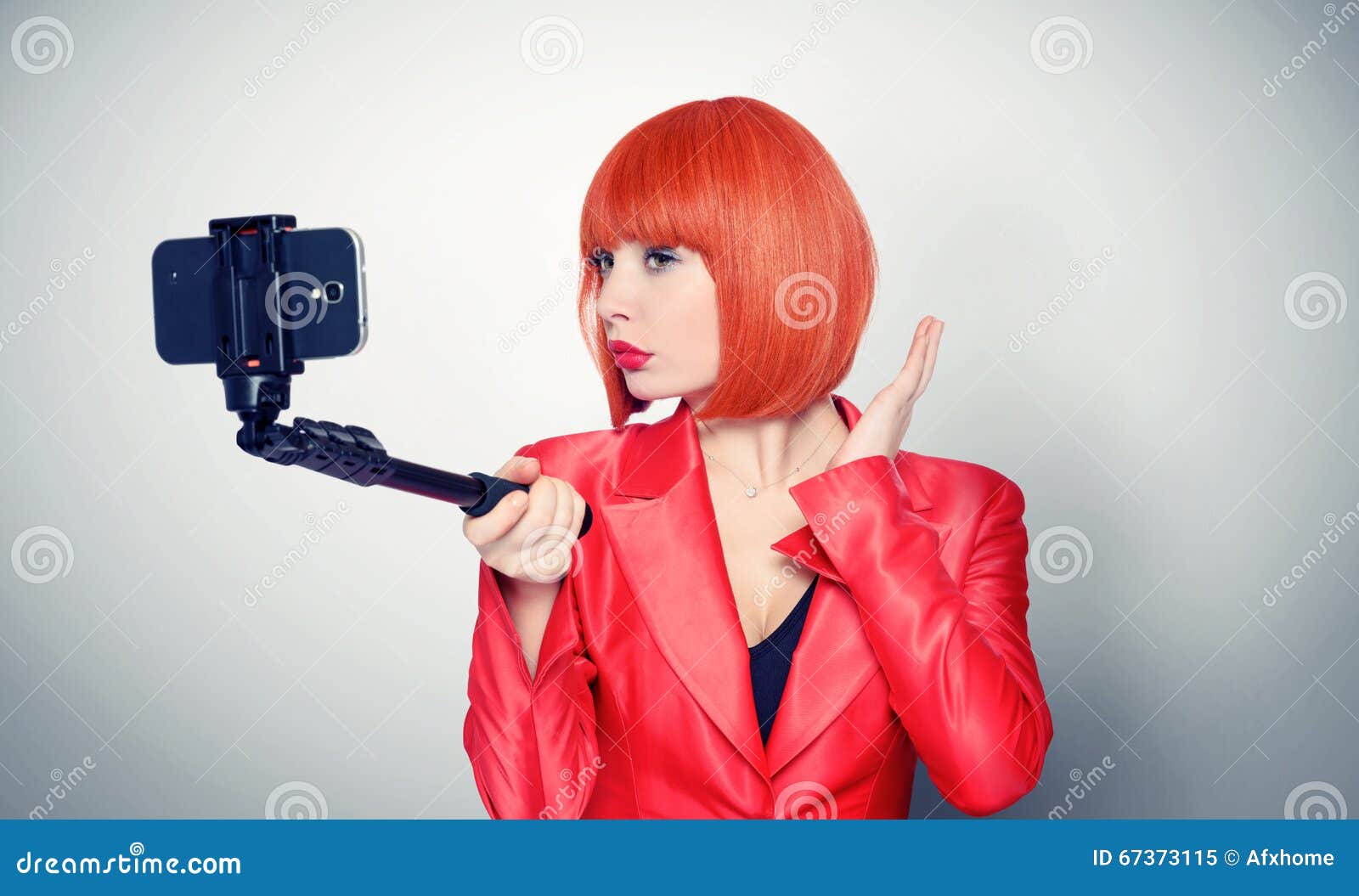 young glamor girl in red making selfie with a stick